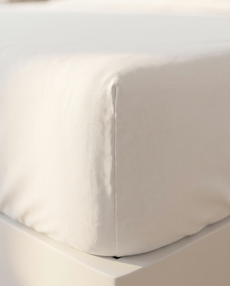 Corner of a white percale fitted sheet stretched over a mattress.
